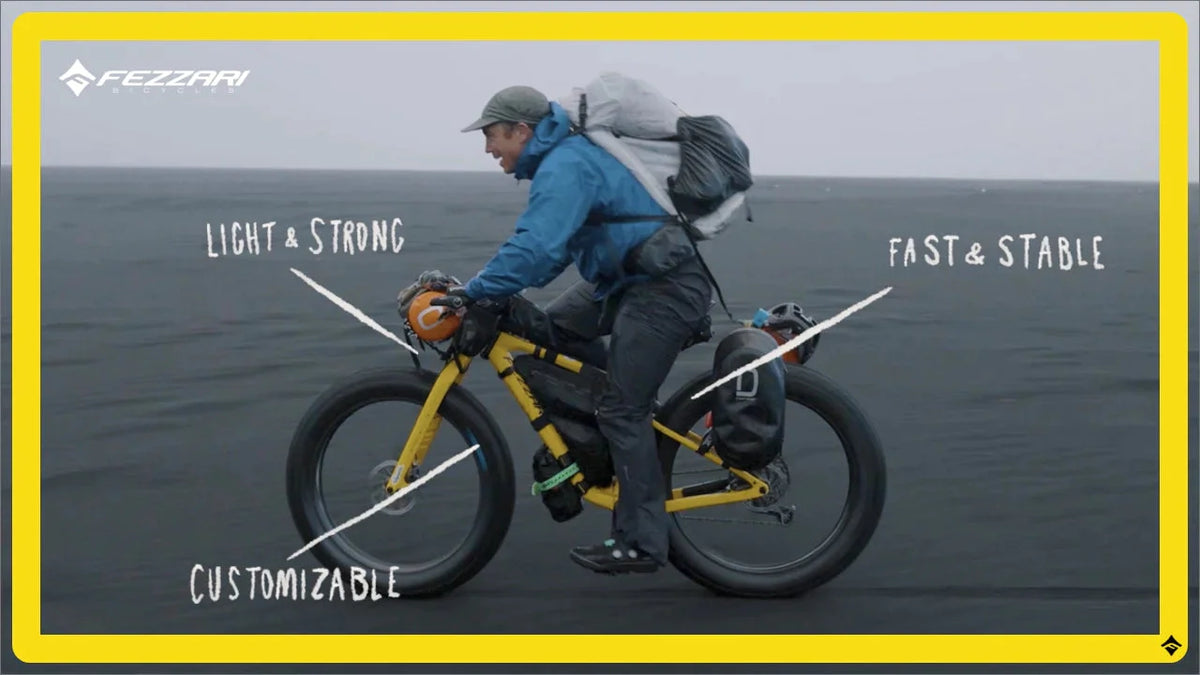 Rider on a loaded yellow fat bike on a black sand beach with Light & Strong, Fast & Stable labels
