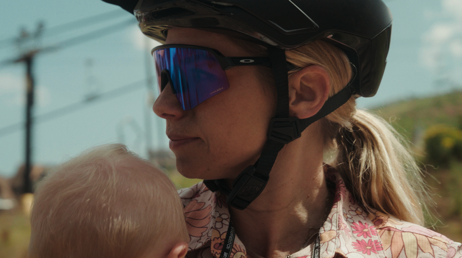 Rachel Strait in a black helmet and sunglasses with a baby's head in the foreground