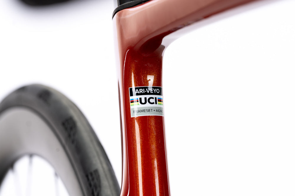 Orange Veyo seat tube with an Ari-Veyo frameset sticker and UCI label