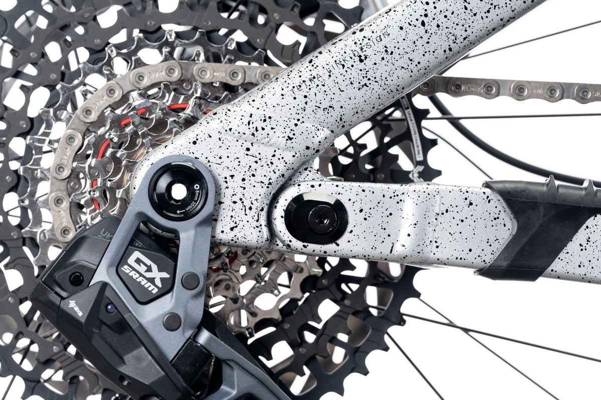 Speckled white frame chainstay with a SRAM GX derailleur and cassette