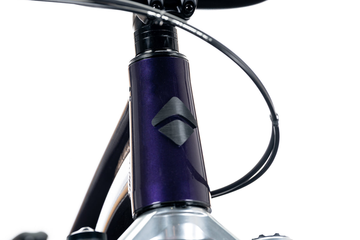 Purple 801 head tube with the Ari diamond badge and a cable looping past
