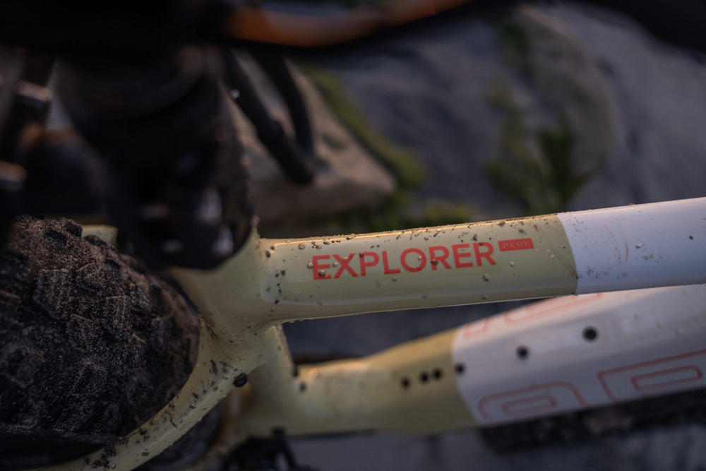 Explorer Peak top tube logo in yellow and white, splashed with trail grit