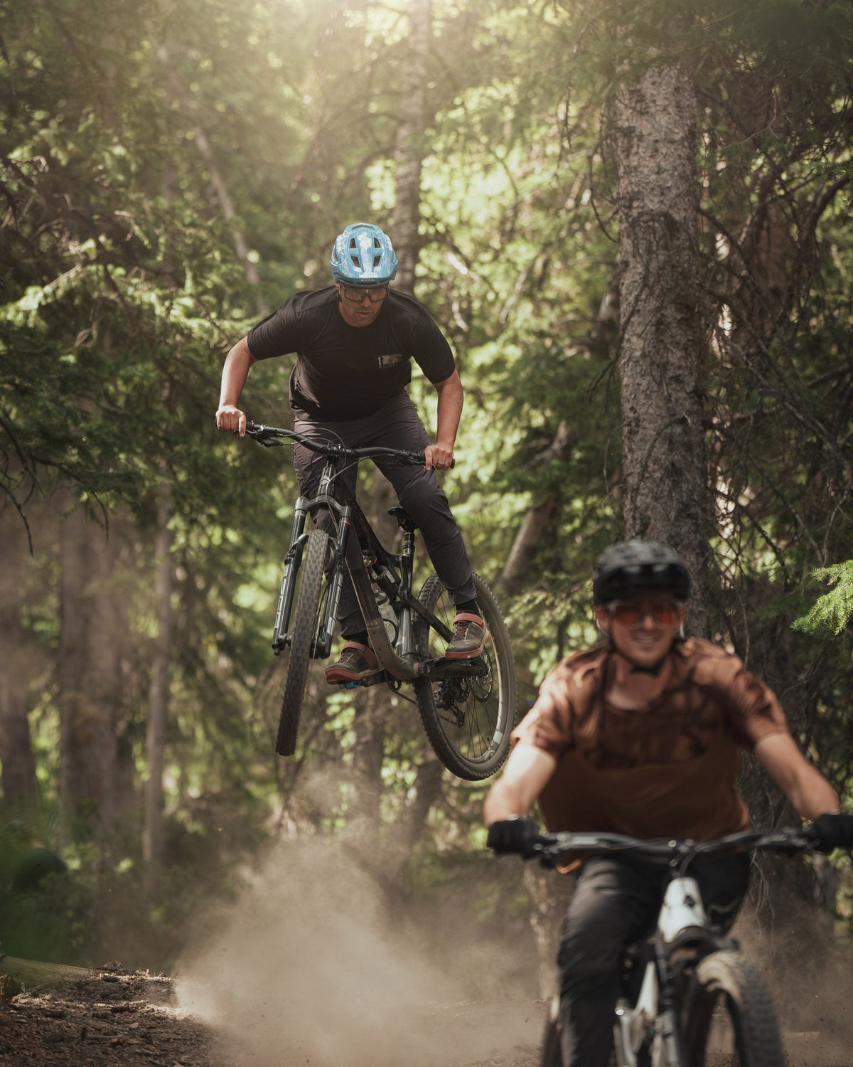Rider jumping the La Sal Peak on a dusty forest trail while another rider follows