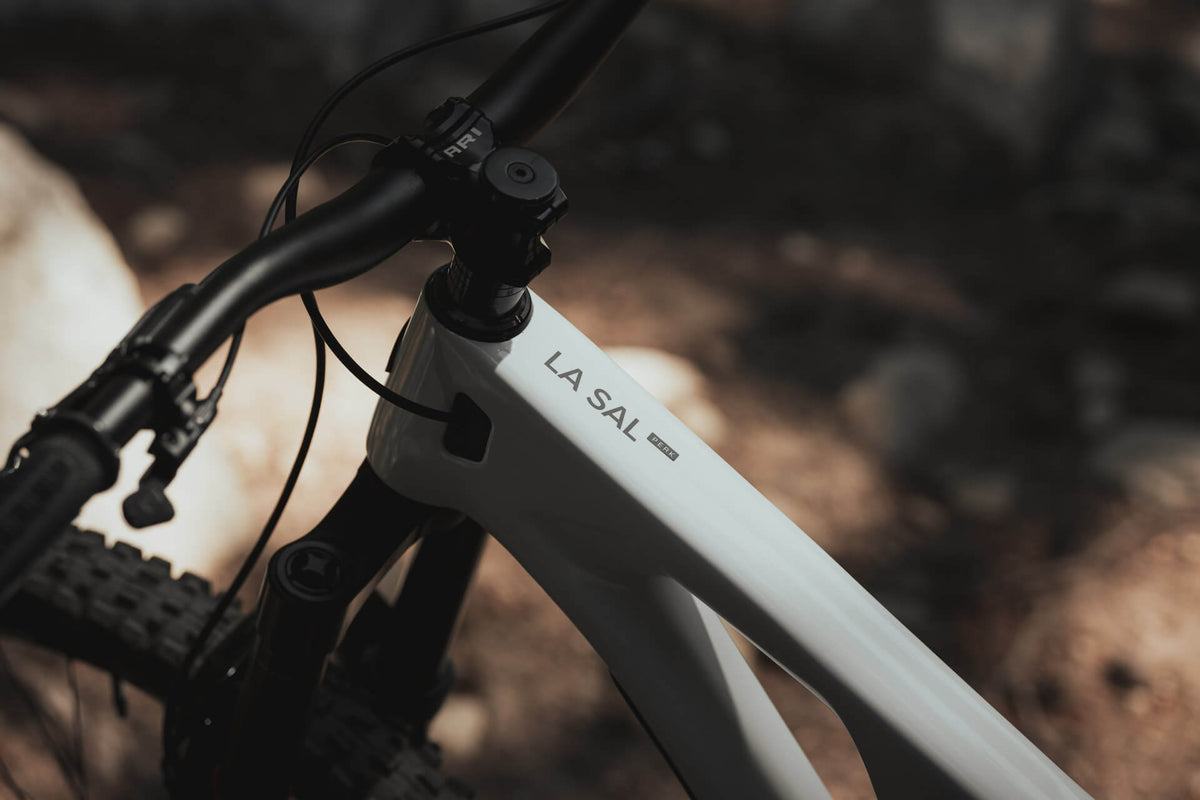 Close-up of the La Sal name on the top tube of a white frame beside the stem and handlebar