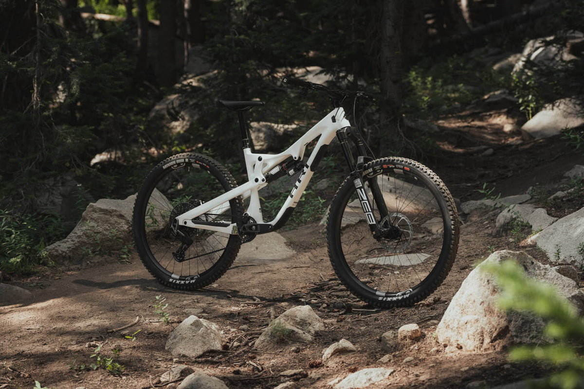 Low-angle wide shot of a white La Sal on a rocky forest trail with boulders around it