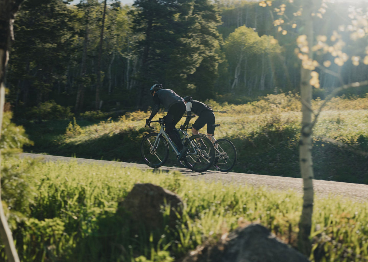 Two riders on Suncrest bikes on a sunlit forest road