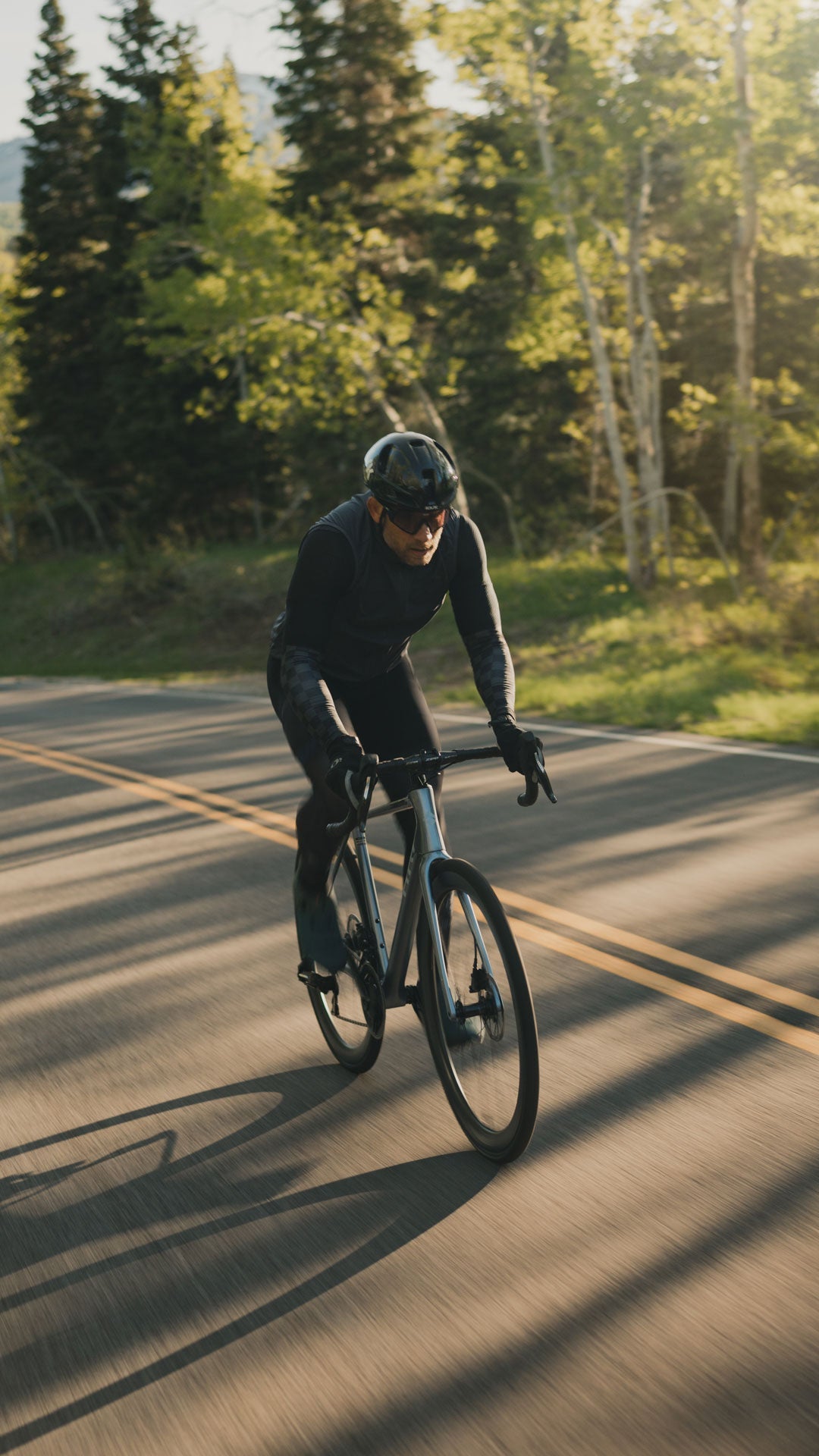 Rider on a silver Suncrest coming toward the camera on a tree-lined road